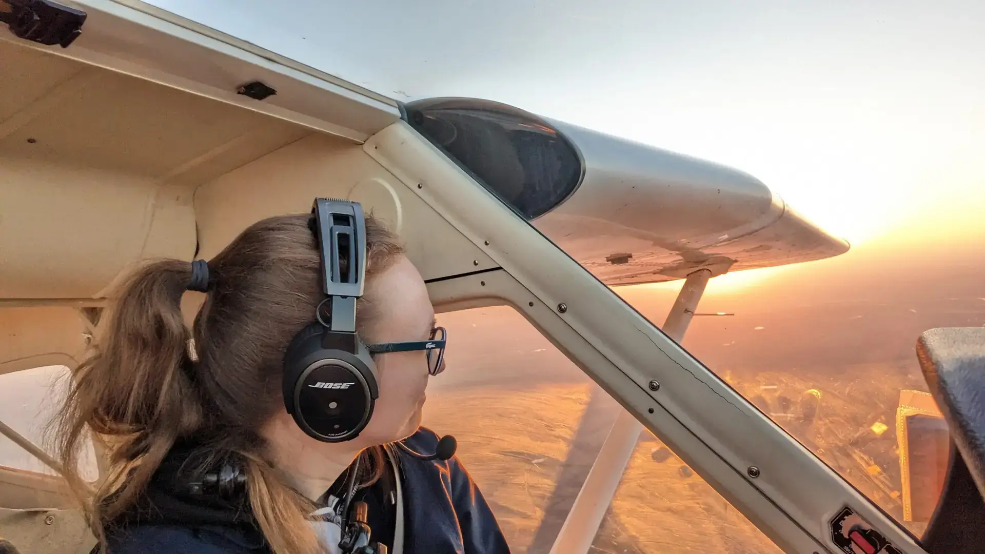 Pilot standing beside a training airplane in bright sunlight